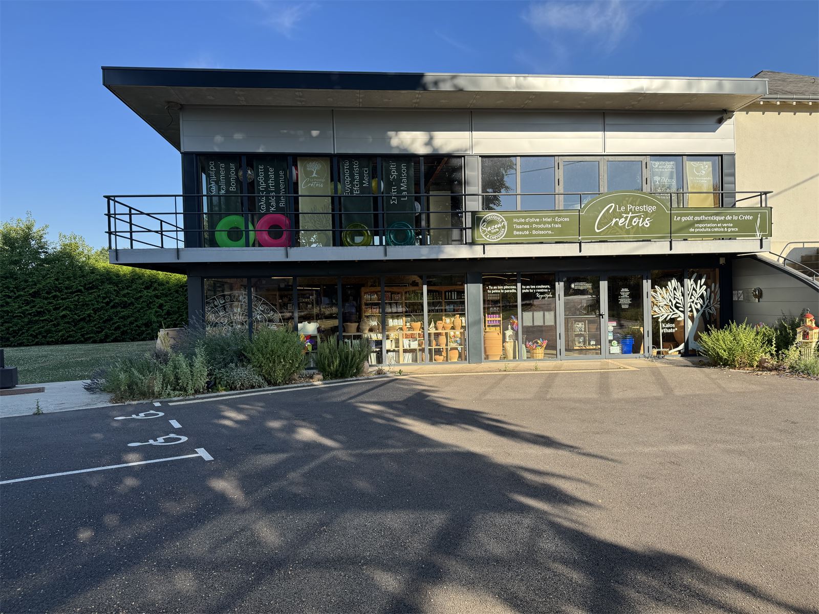 Façade de notre épicerie grecque à Messei, dans l'Orne - bannière verte Le Prestige Crétois et vitrines décorées