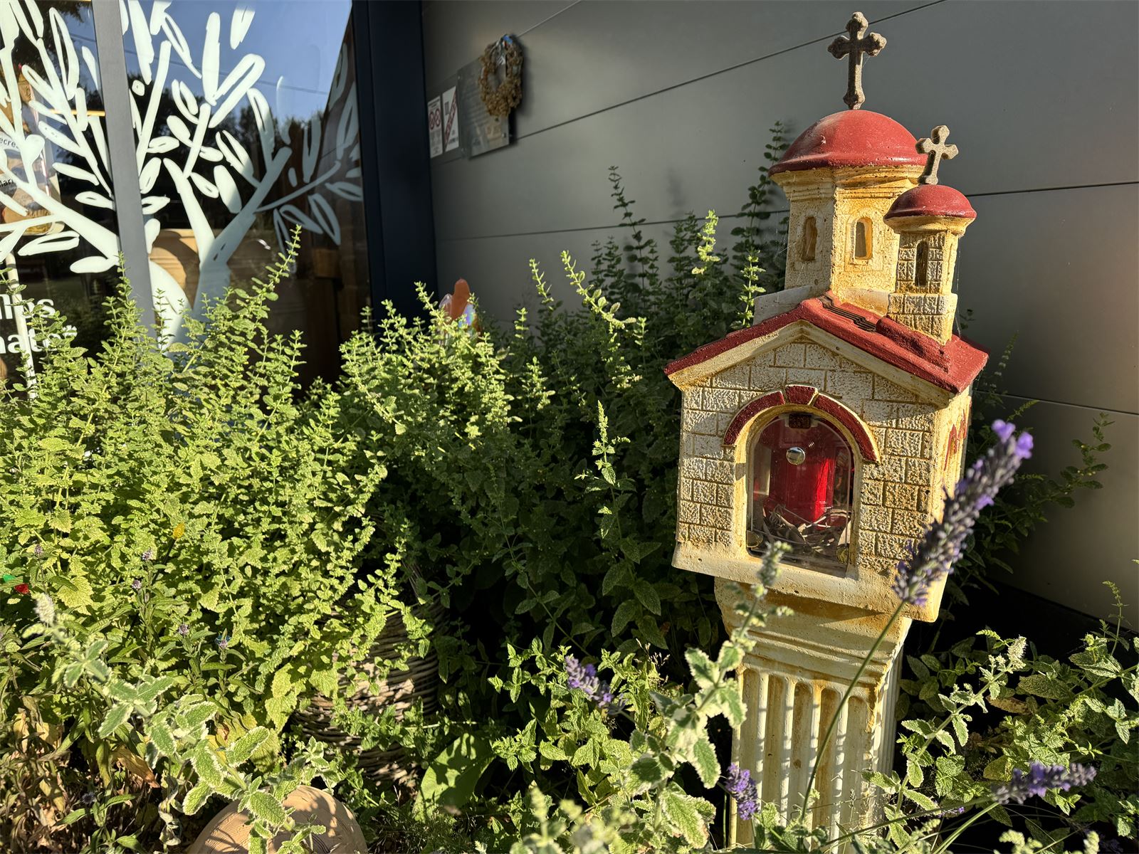 Chapelle orthodoxe miniature entourée de lavande et d'aromates, dans le jardin de l'épicerie grecque de Messei