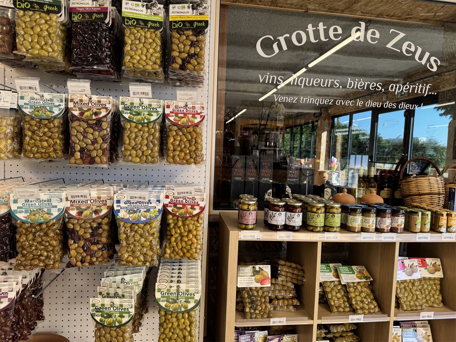Mur d'olives grecques et vitrine de la Grotte de Zeus, la cave de la boutique